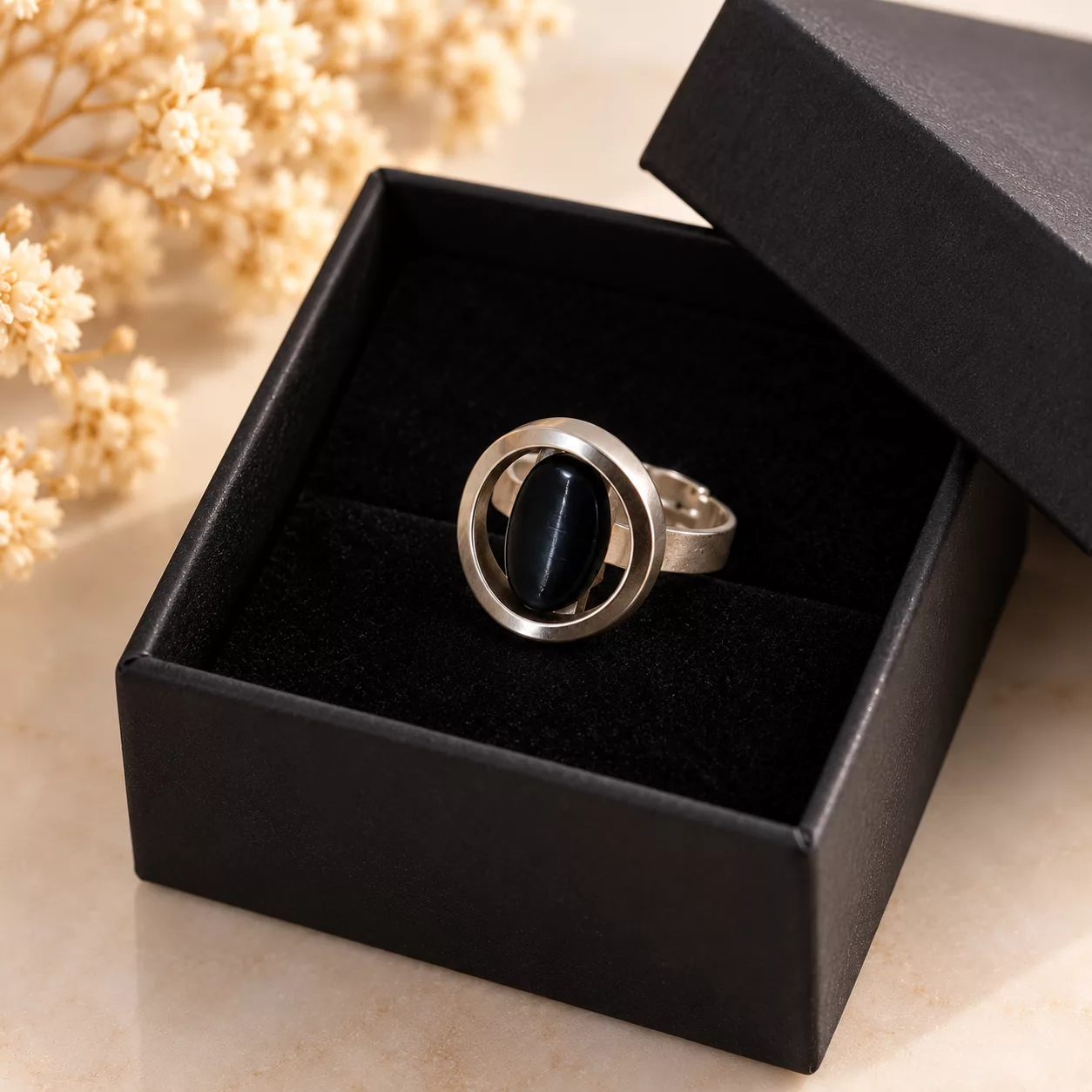 Bague Éclipse avec bouton ajouré bleu nuit présentée dans une boîte cadeau noire