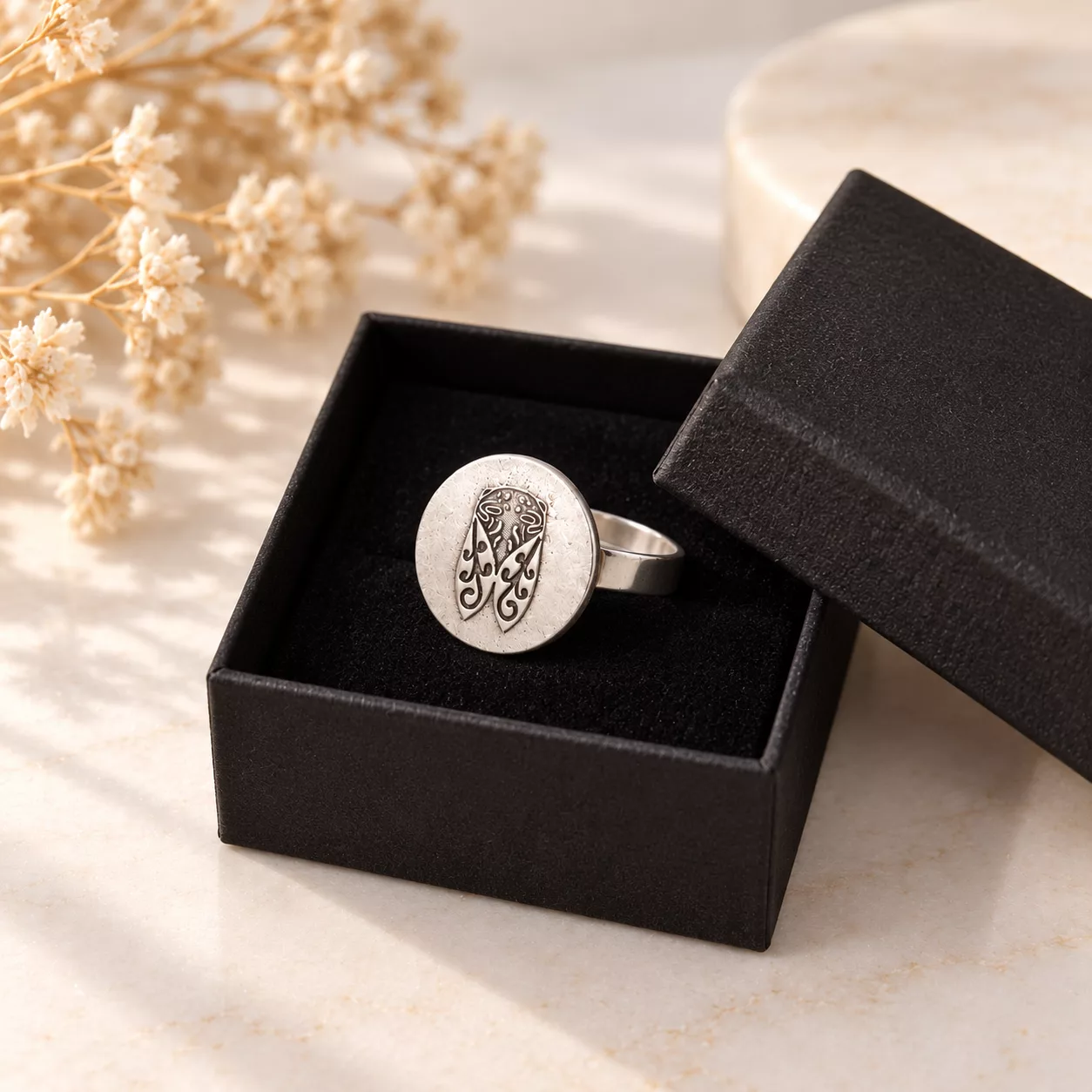 Bague Cigale argentée présentée dans une boîte cadeau noire