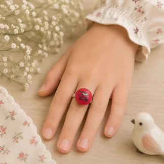 Enfant portant une bague réglable créée à partir d'un ancien bouton rose représentant un petit oiseau