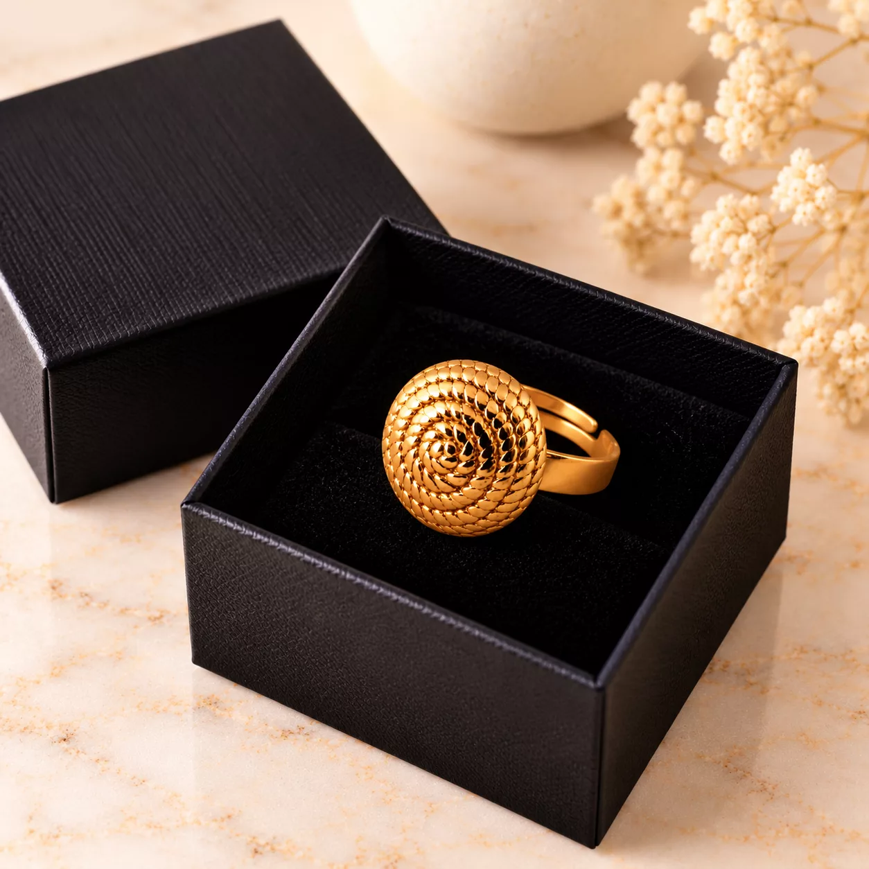 Bague Tourbillon présentée dans une boîte cadeau noire, avec son motif circulaire doré