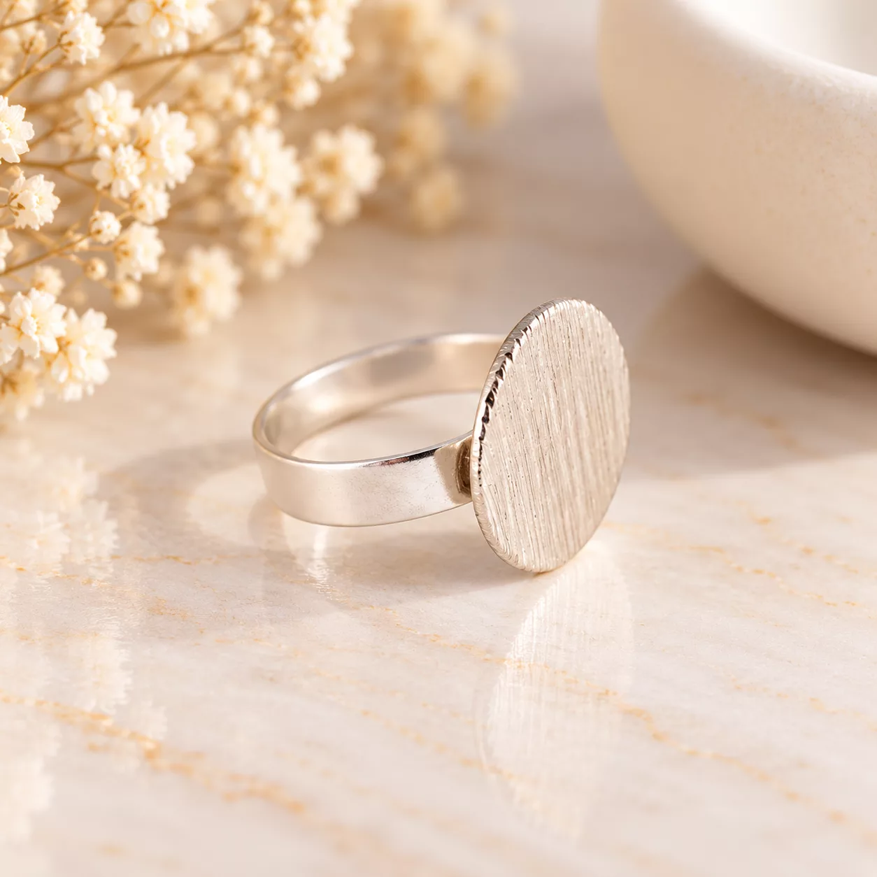 Vue de profil de la bague Minimaliste montrant son disque argenté texturé et son anneau