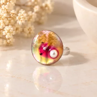 Bague Huître aux reflets nacrés multicolores et perles blanches sur fond crème