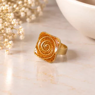 Bague Labyrinthe à motif spirale dorée sur une surface en marbre clair