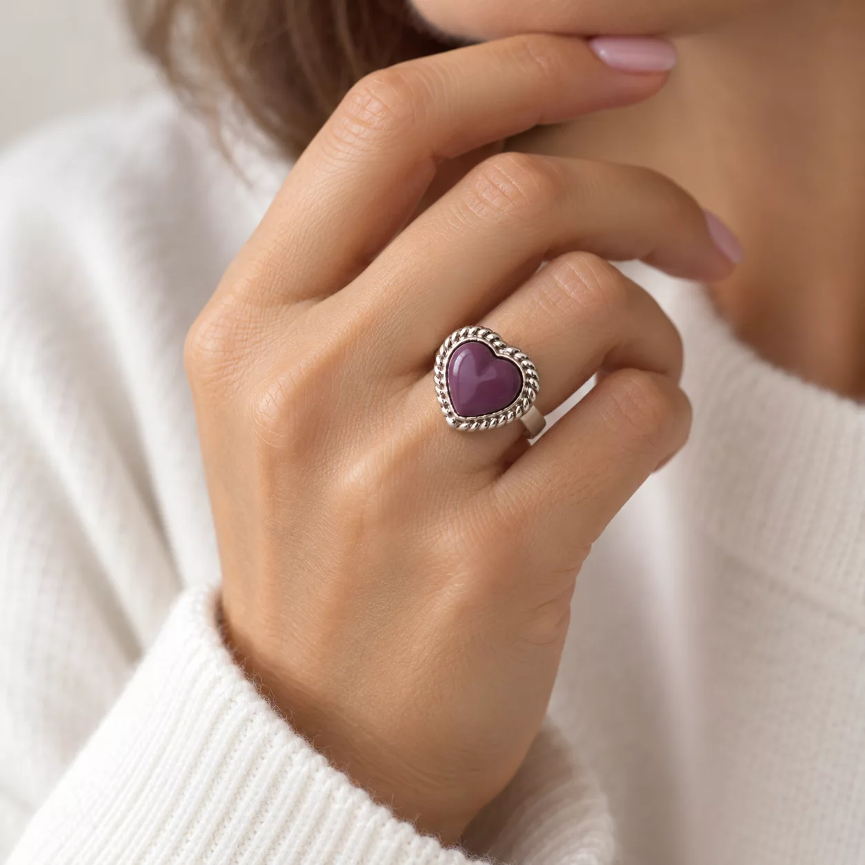 Bague Cœur violet portée au doigt avec son motif en cœur violet et son contour argenté torsadé