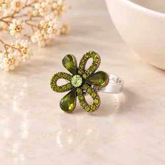 Bague fleur strass verts sur un décor crème, avec pétales en forme de goutte