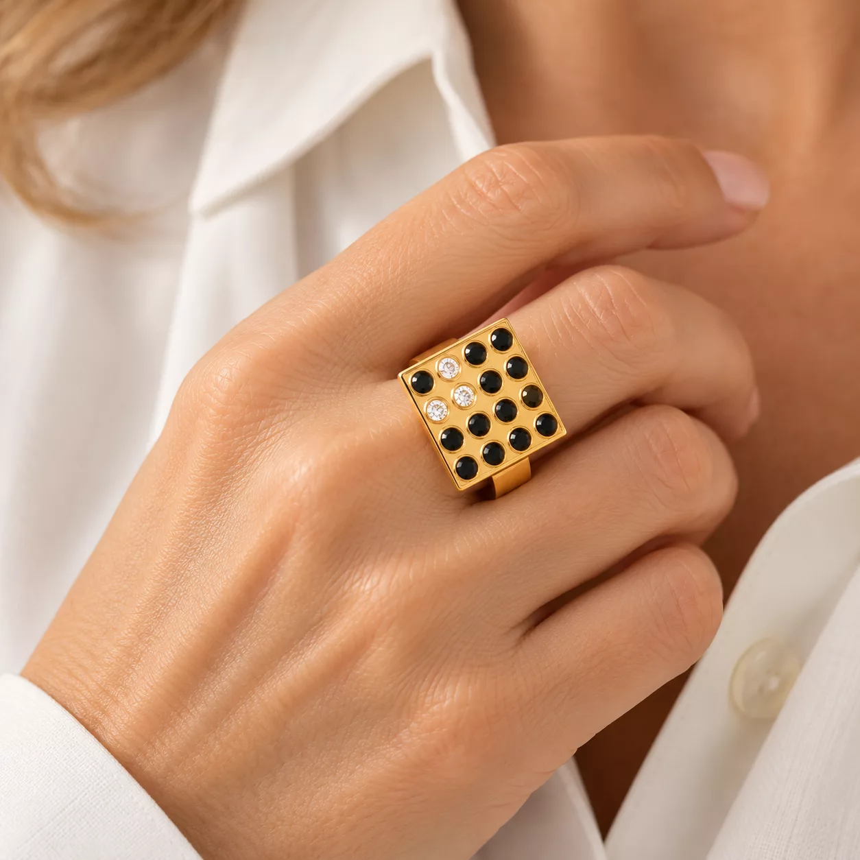 Bague Carré Luxe dorée à strass noirs et blancs portée au doigt
