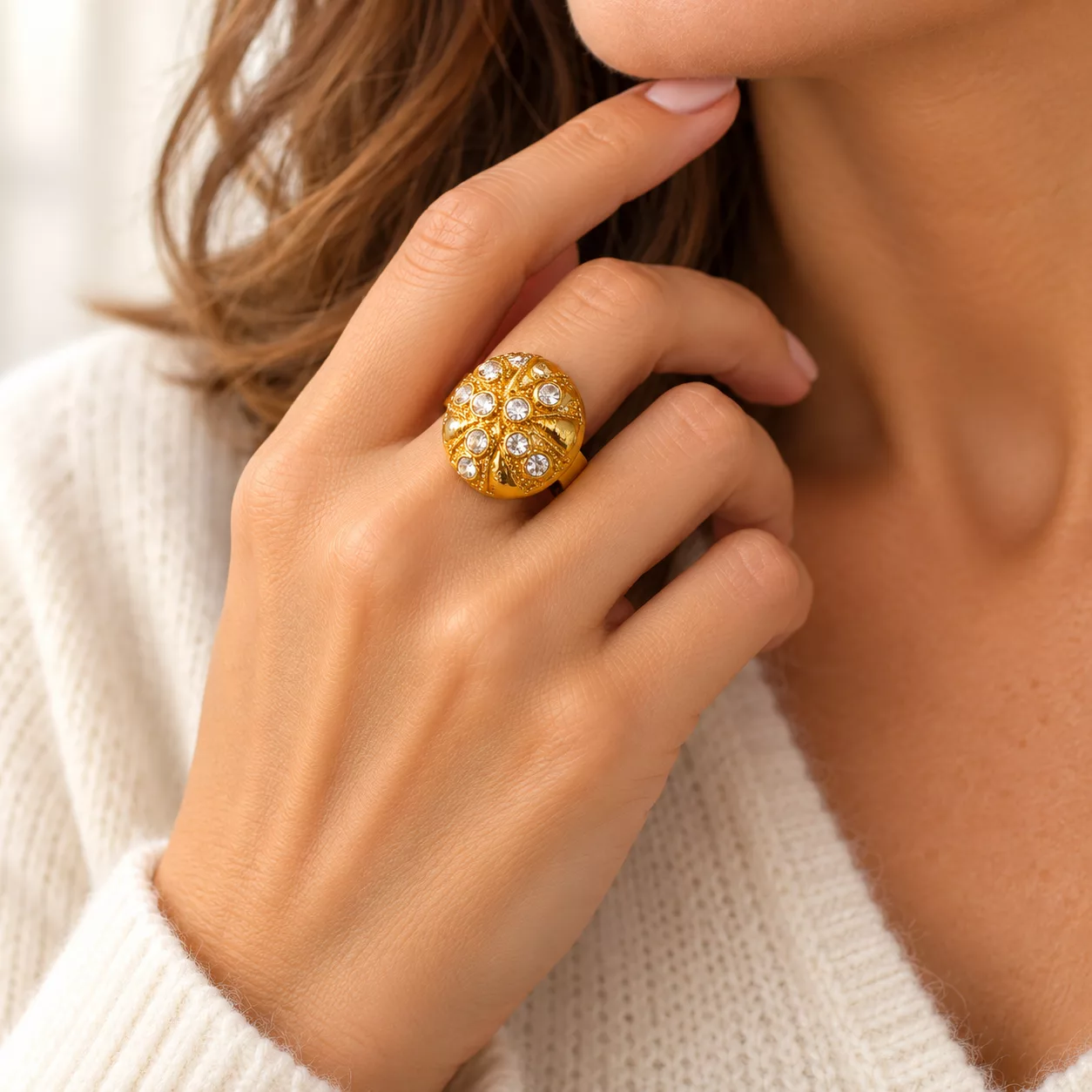 Bague dorée vintage portée au doigt, ornée de strass blancs et de reliefs décoratifs