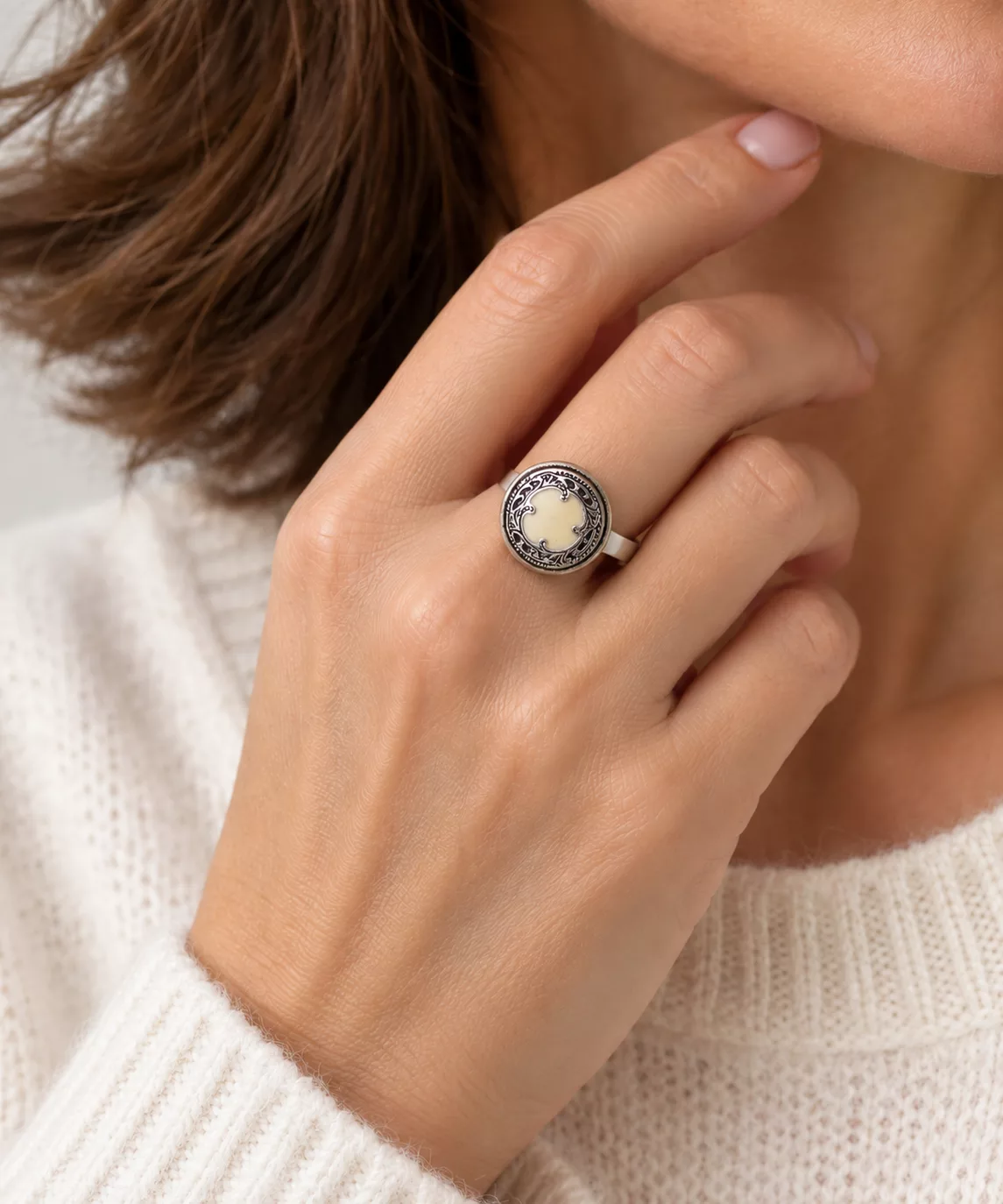 Bague Aura portée à la main, avec centre ivoire et arabesques argentées