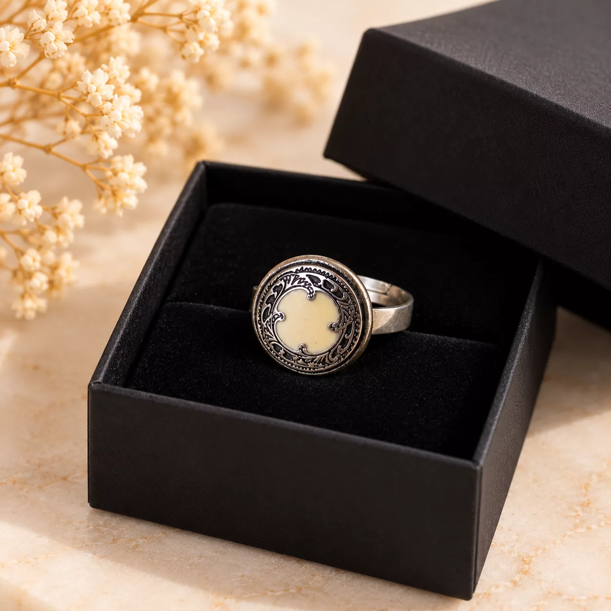 Bague Aura aux arabesques argentées présentée dans sa boîte cadeau noire