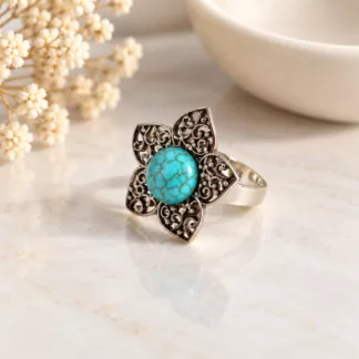 Bague fleur turquoise Lotus avec cinq pétales en métal argenté ajouré sur fond crème