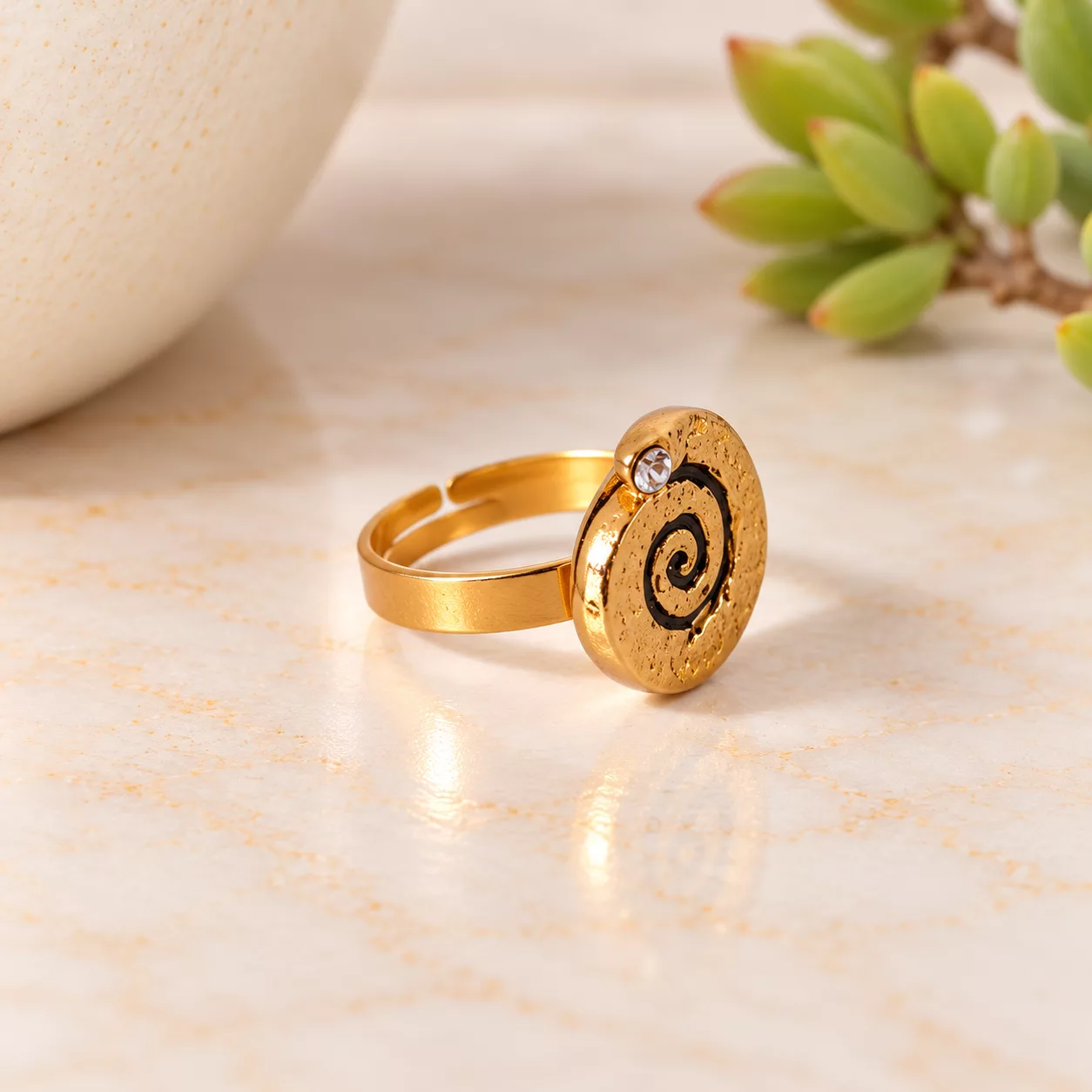 Vue de profil de la bague Spirale d’or mettant en valeur le relief du bouton et son anneau doré ajustable