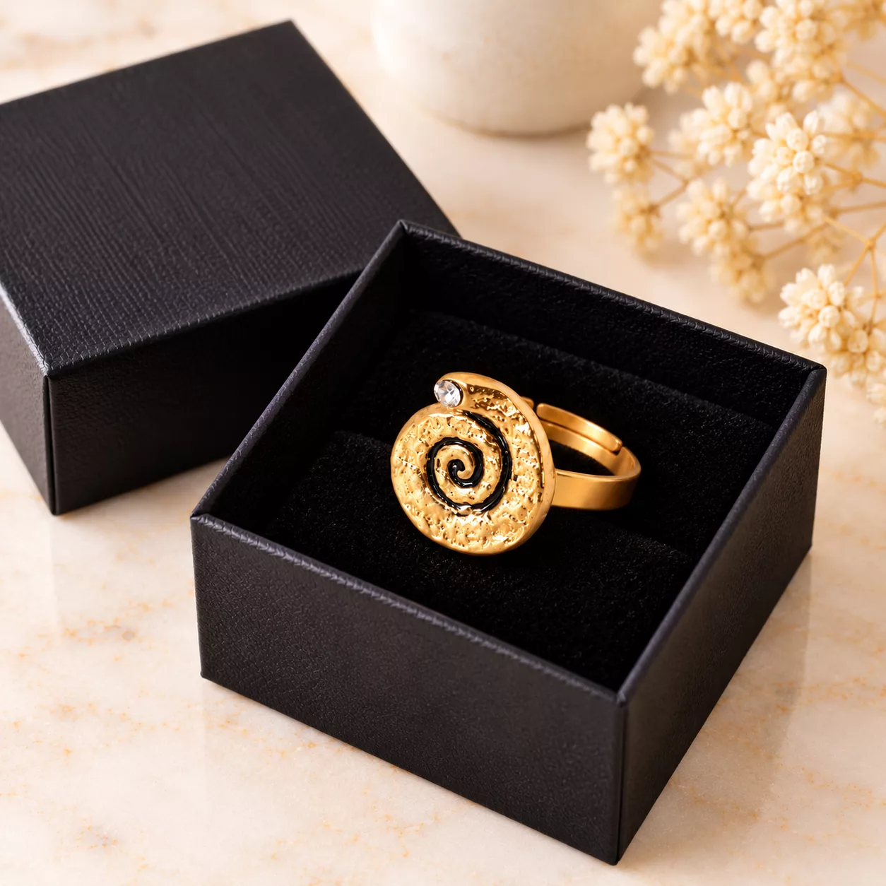 Bague Spirale d’or présentée dans une boîte cadeau noire, avec son motif en spirale et son strass
