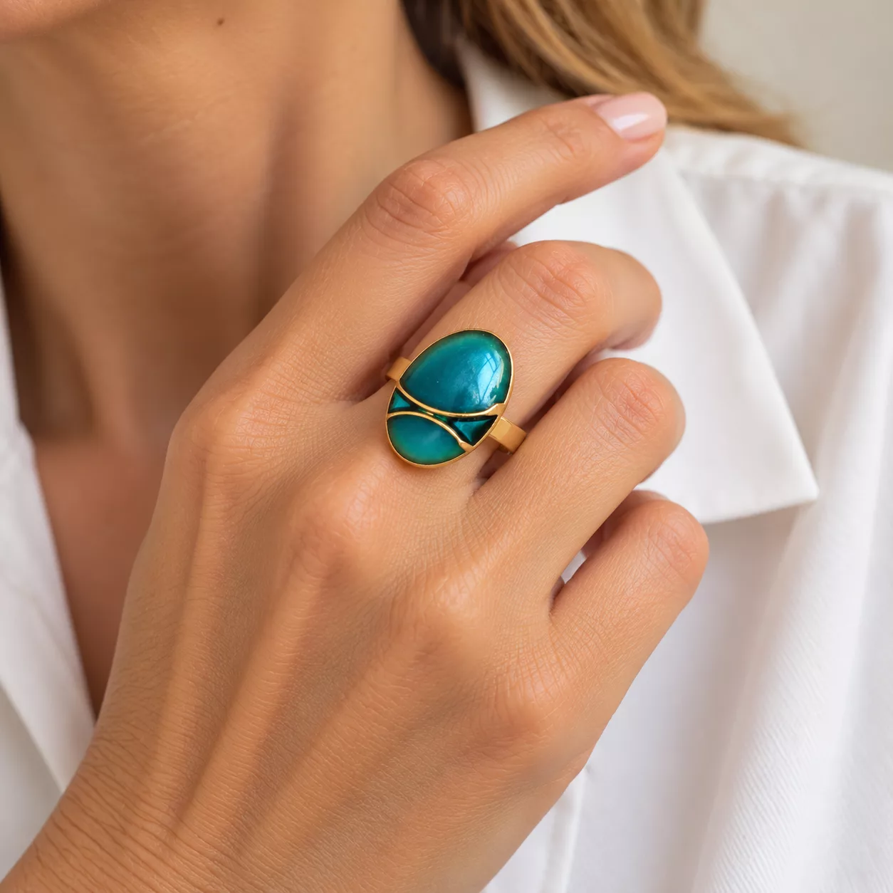 Bague Éclat turquoise portée au doigt, bouton ovale bleu-vert à décor doré