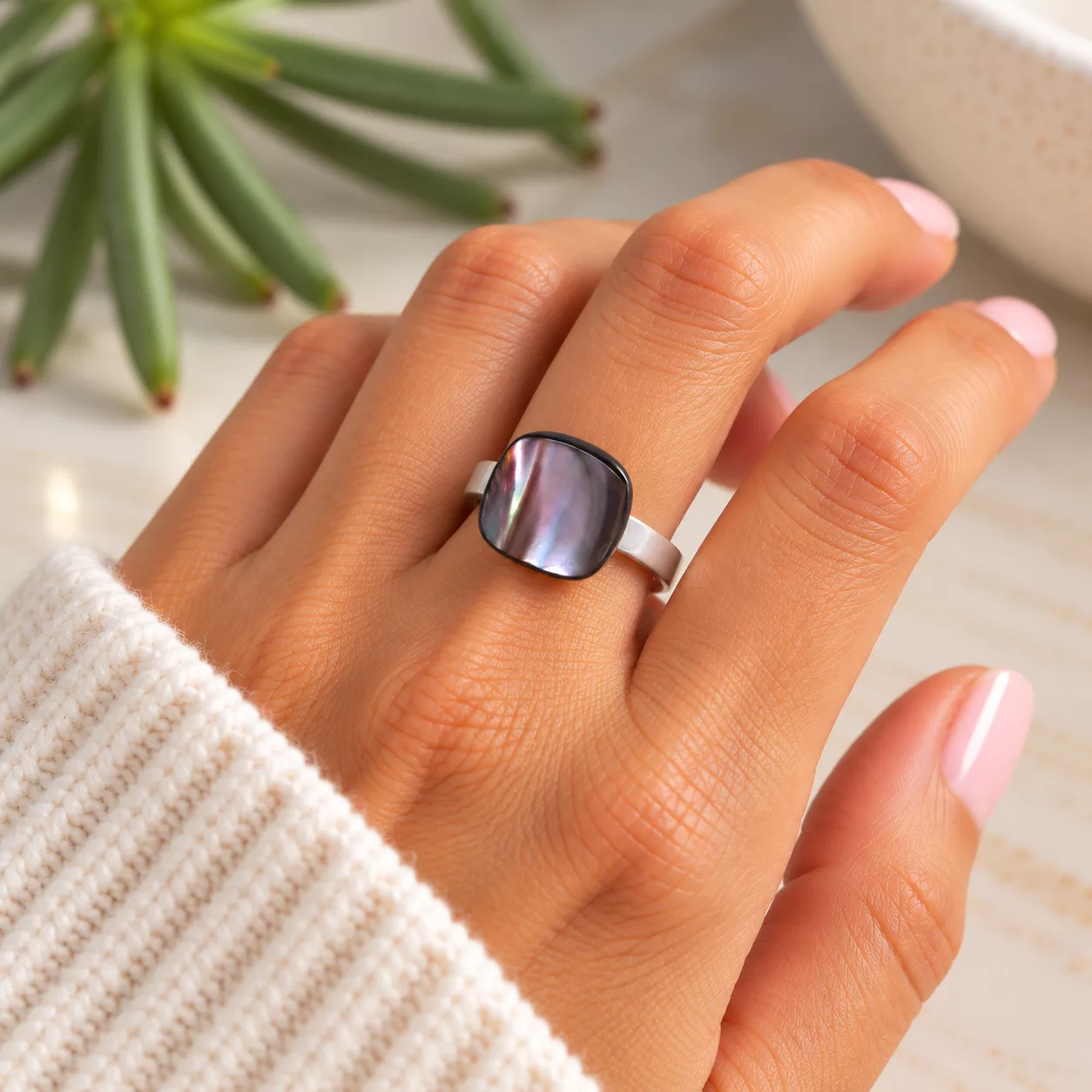 Bague Mira carrée en nacre naturelle aux reflets prune et violets portée au doigt