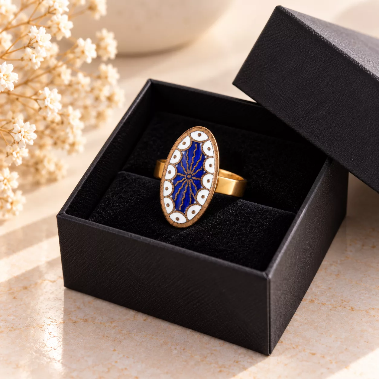 Bague Ovale Céleste présentée dans une boîte cadeau noire, avec décor émaillé bleu et blanc
