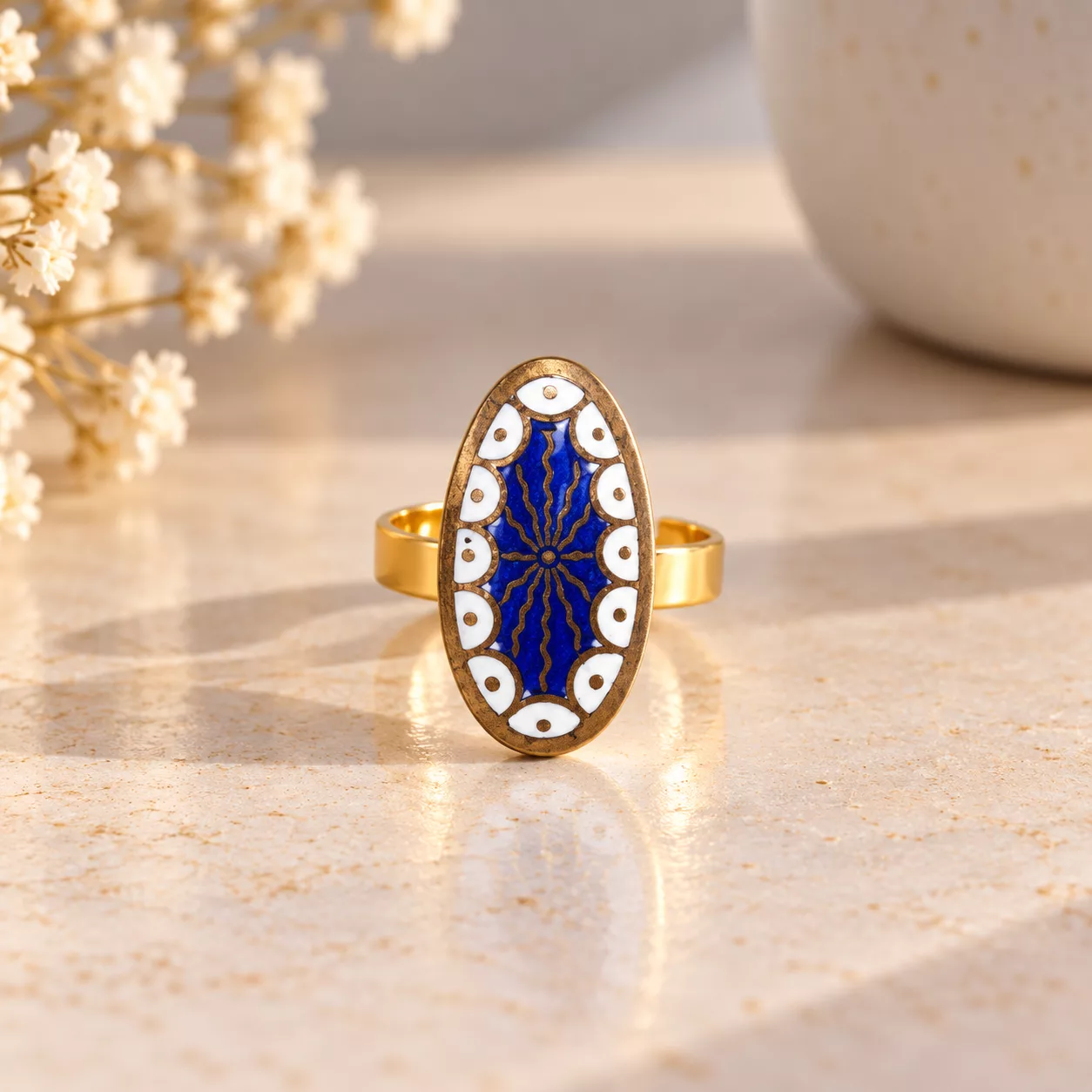 Vue de face de la bague Ovale Céleste avec motifs blancs festonnés et lignes cuivrées sur fond bleu