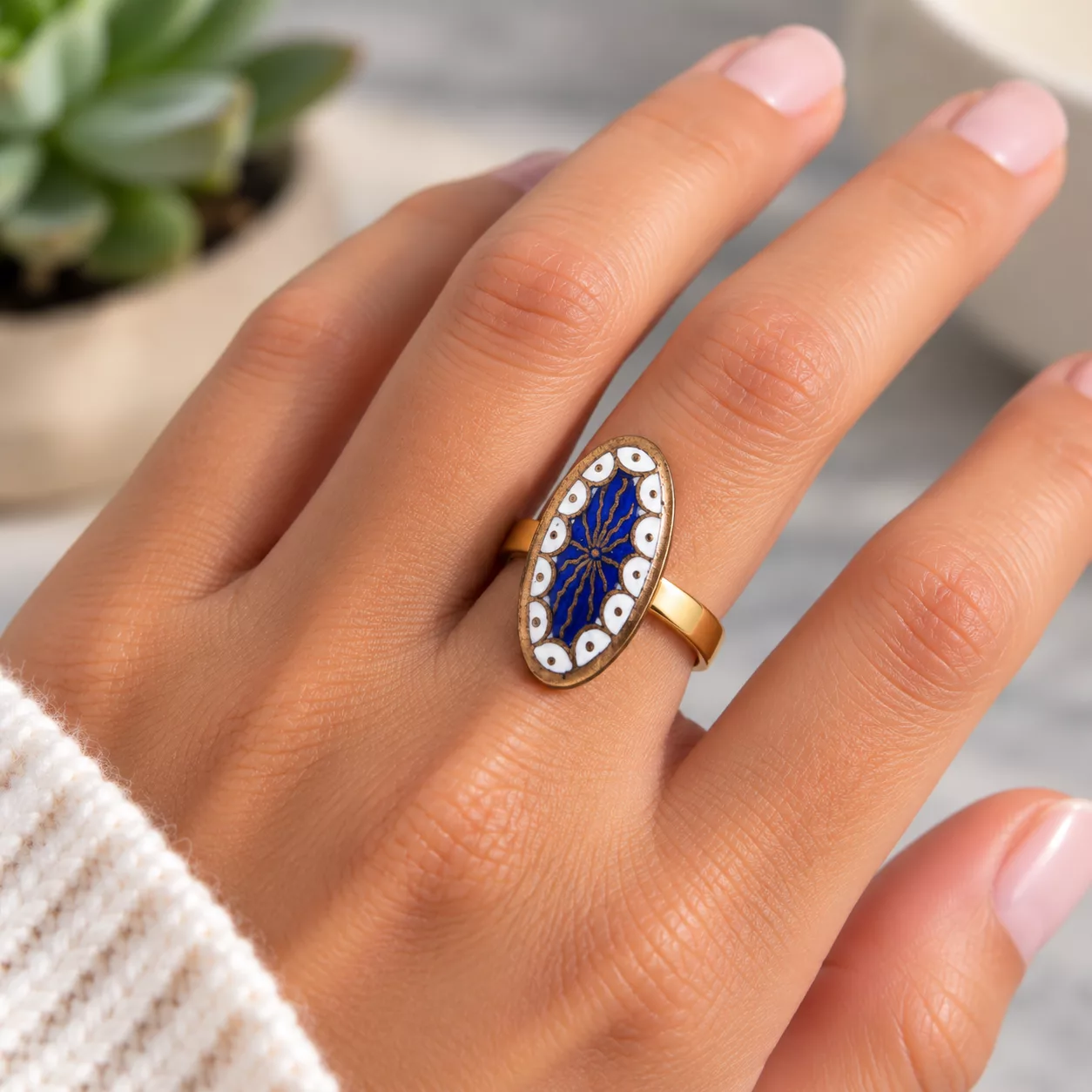 Bague ovale émaillée Ovale Céleste portée au doigt, avec décor bleu, blanc et cuivré