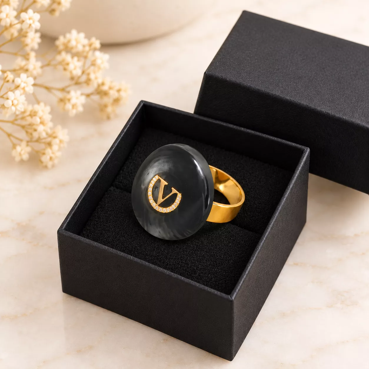 Bague Le V au médaillon gris anthracite présentée dans une boîte cadeau noire