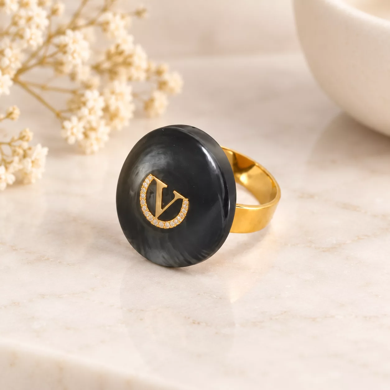 Bague bouton haute couture Le V, médaillon gris anthracite effet corne et anneau doré sur fond crème