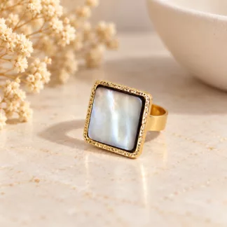 Bague Nacre carrée avec plateau nacré et monture dorée sur fond crème