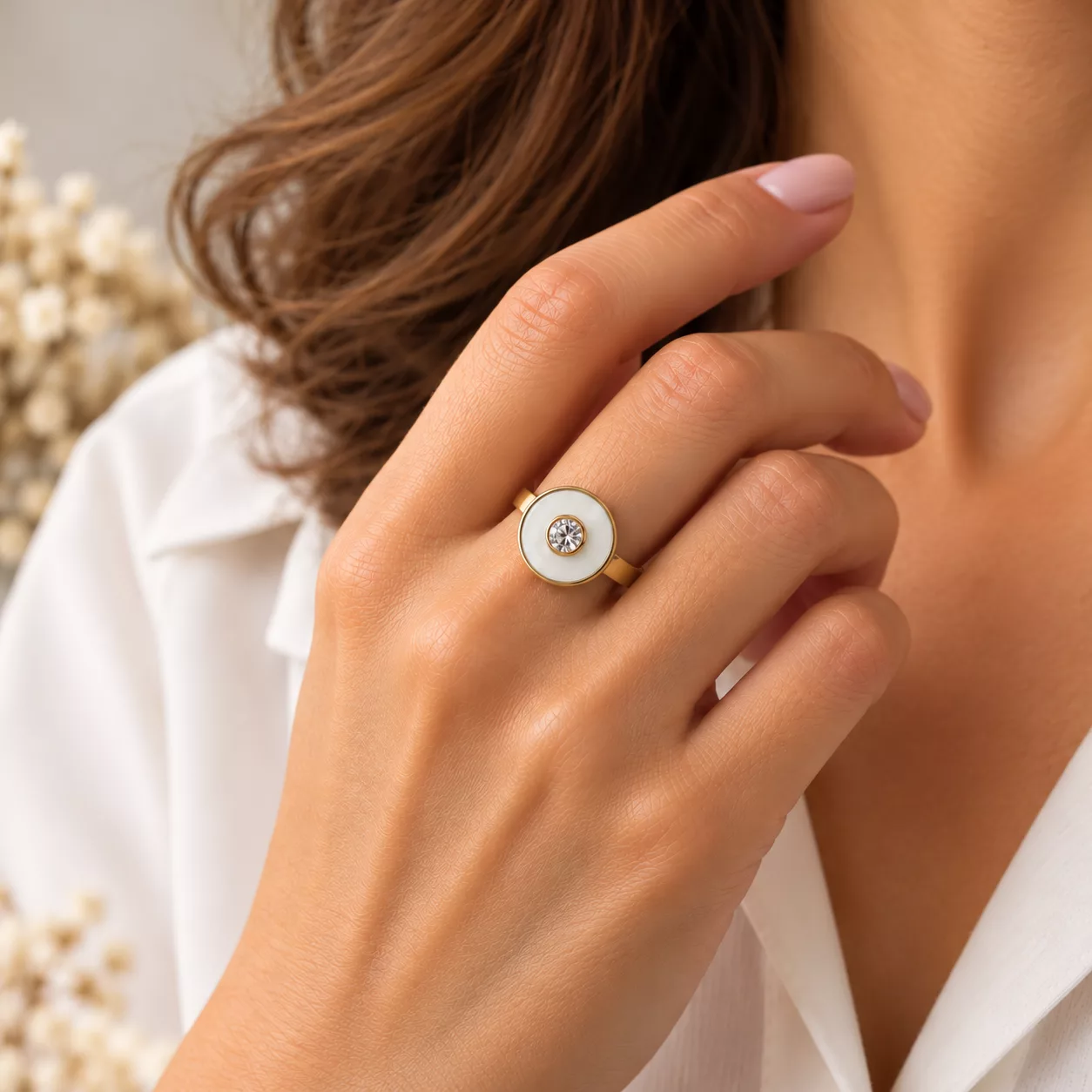 Bague Albane portée sur la main, avec son motif blanc et son strass scintillant