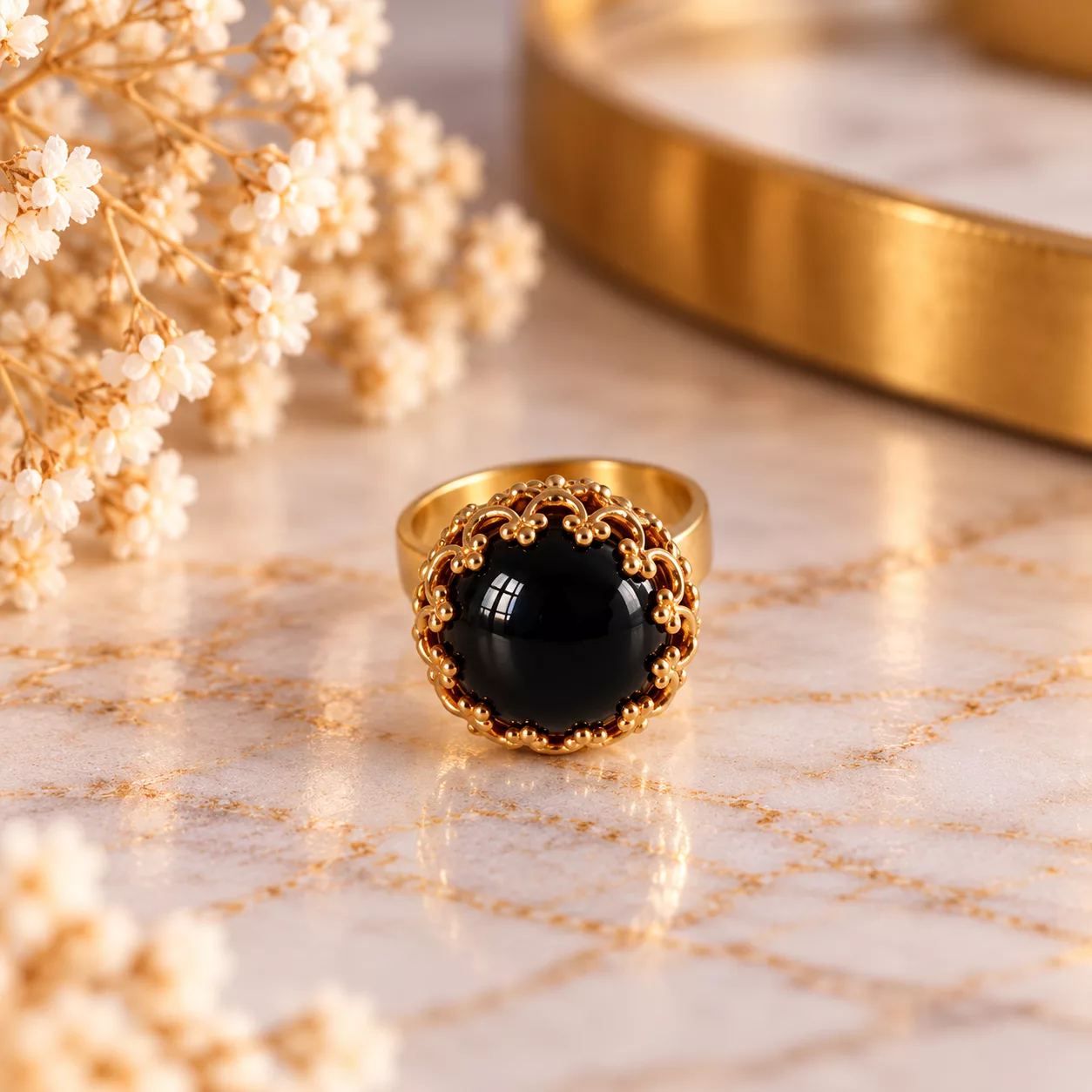 Vue de face de la bague Arabesque avec cabochon noir et arabesques en métal doré