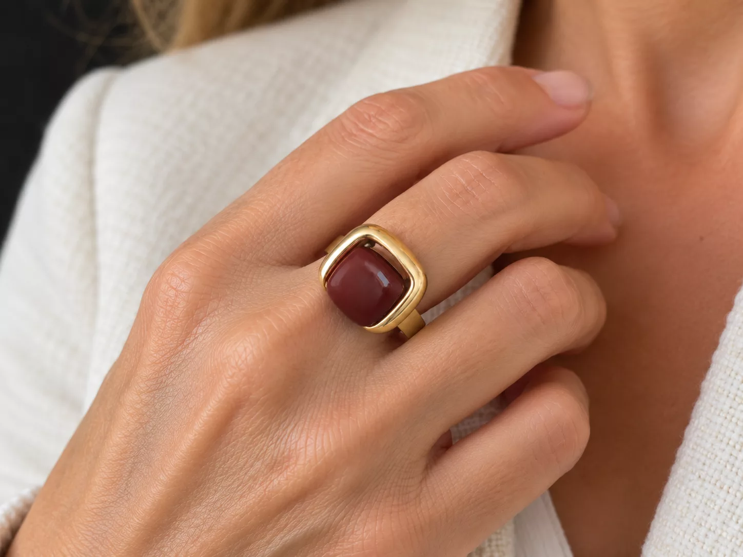 Bague Gina marron portée à la main, monture dorée