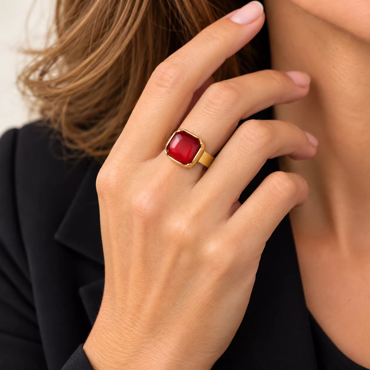 Bague rouge carrée Carmen portée à la main, avec son motif rouge lumineux et doré